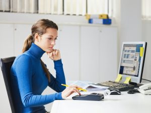 Female Young Secretary Using Calculator In Office
